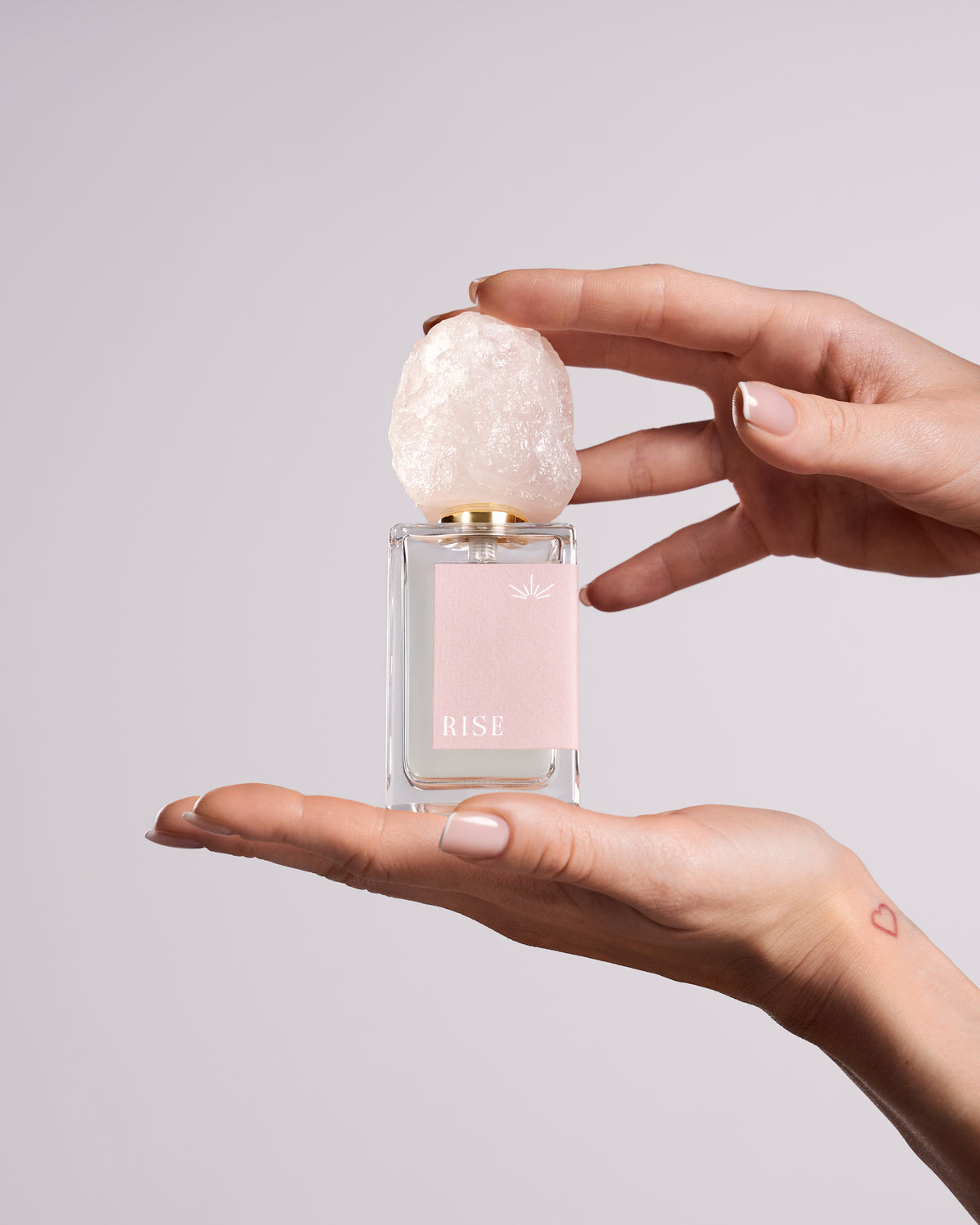 RISE eau de parfum bottle with its rose quartz cap